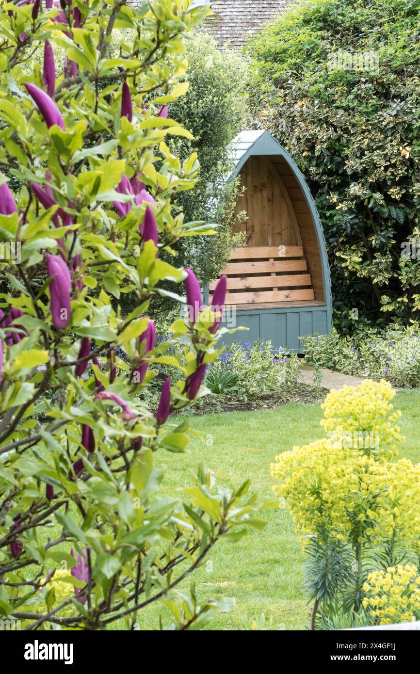 Alter englischer Garten im April mit abgeschiedener Bank. Stockfoto