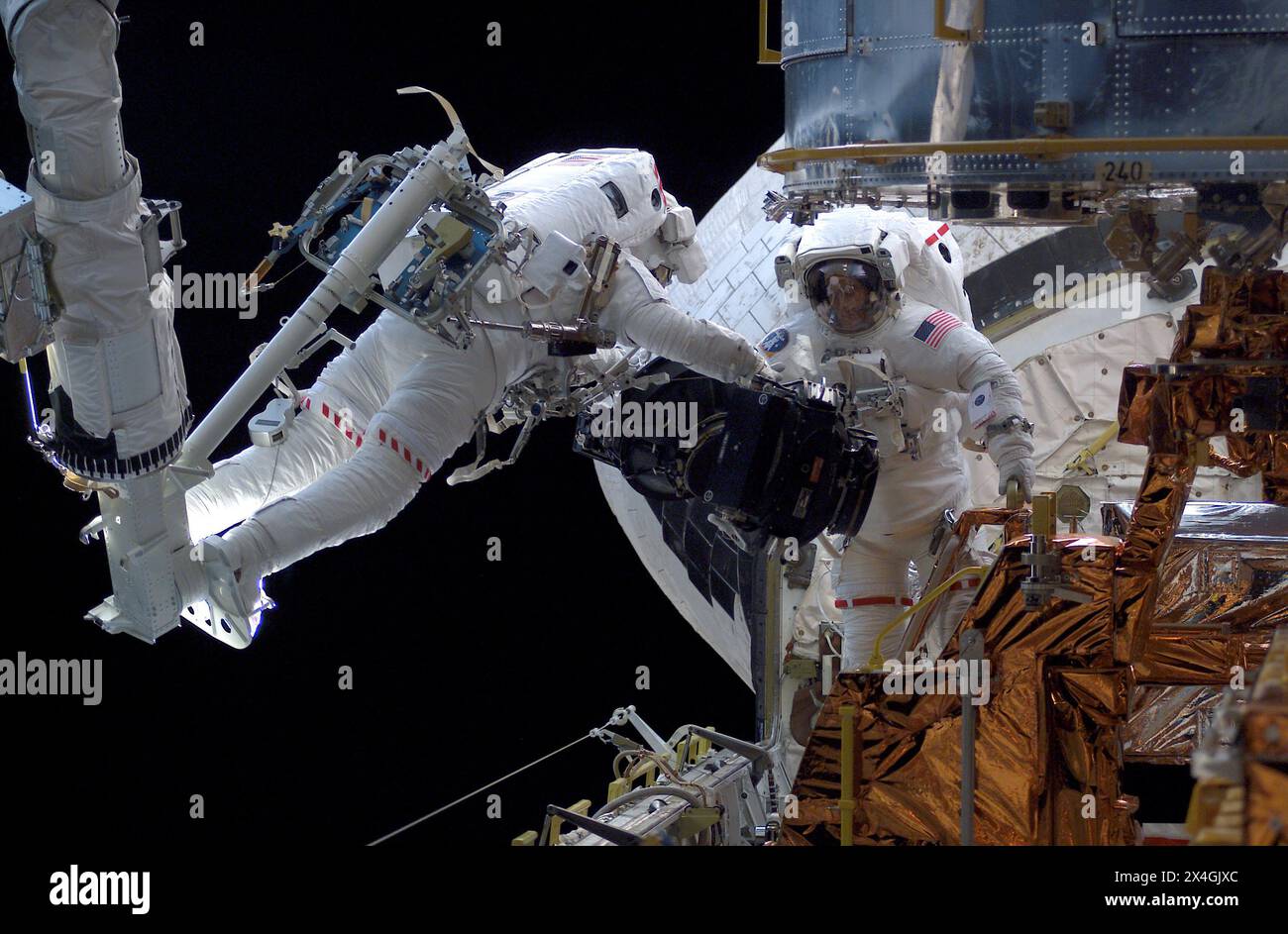 Der Roboterarm des Space Shuttle Columbia, der Astronaut Michael J. Massimino und James H. Newman während der Columbia Mission am zweiten Tag der außerfahrbaren Aktivität (EVA). Stockfoto