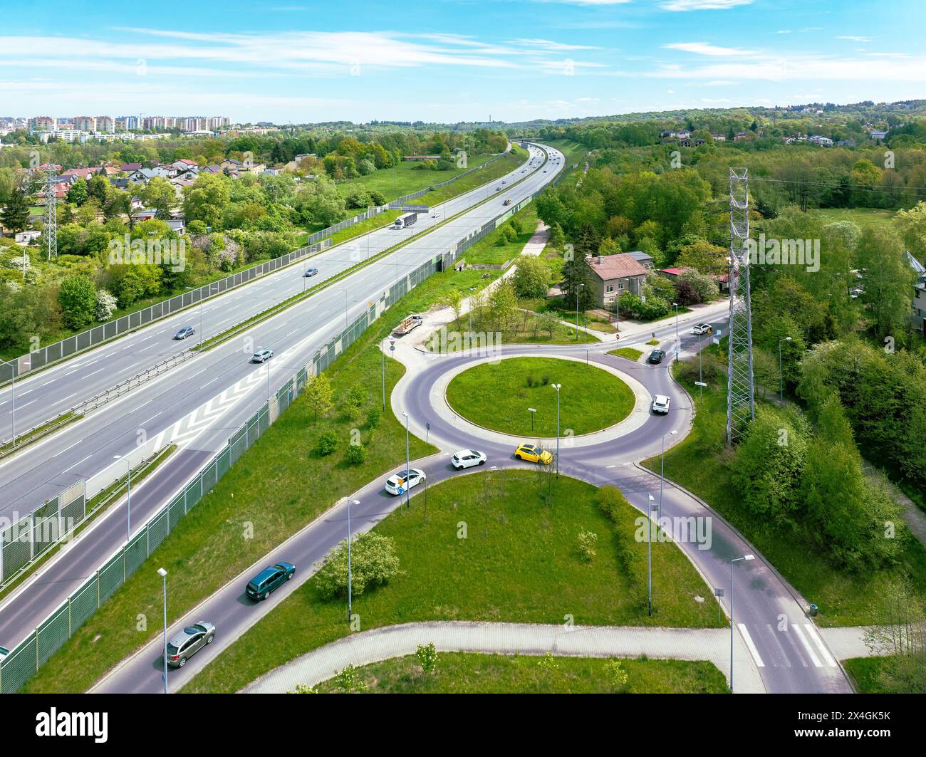 Dreispurige Autobahn A4 in Krakau, Polen. Ein- und Ausstiegsrampe mit einem Kreisverkehr, Autos und Lärmschutzvorrichtungen. Luftaufnahme Stockfoto