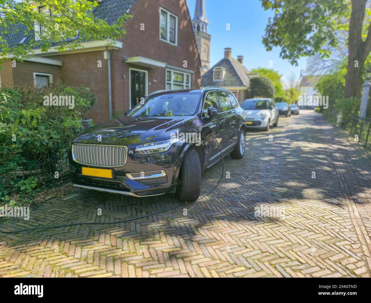Elektrofahrzeug-Aufladung vor einem Haus in den Niederlanden, Öko-Energie und Öko-Strom aus nachhaltiger Quelle zur Versorgung des Ladegeräts Stockfoto