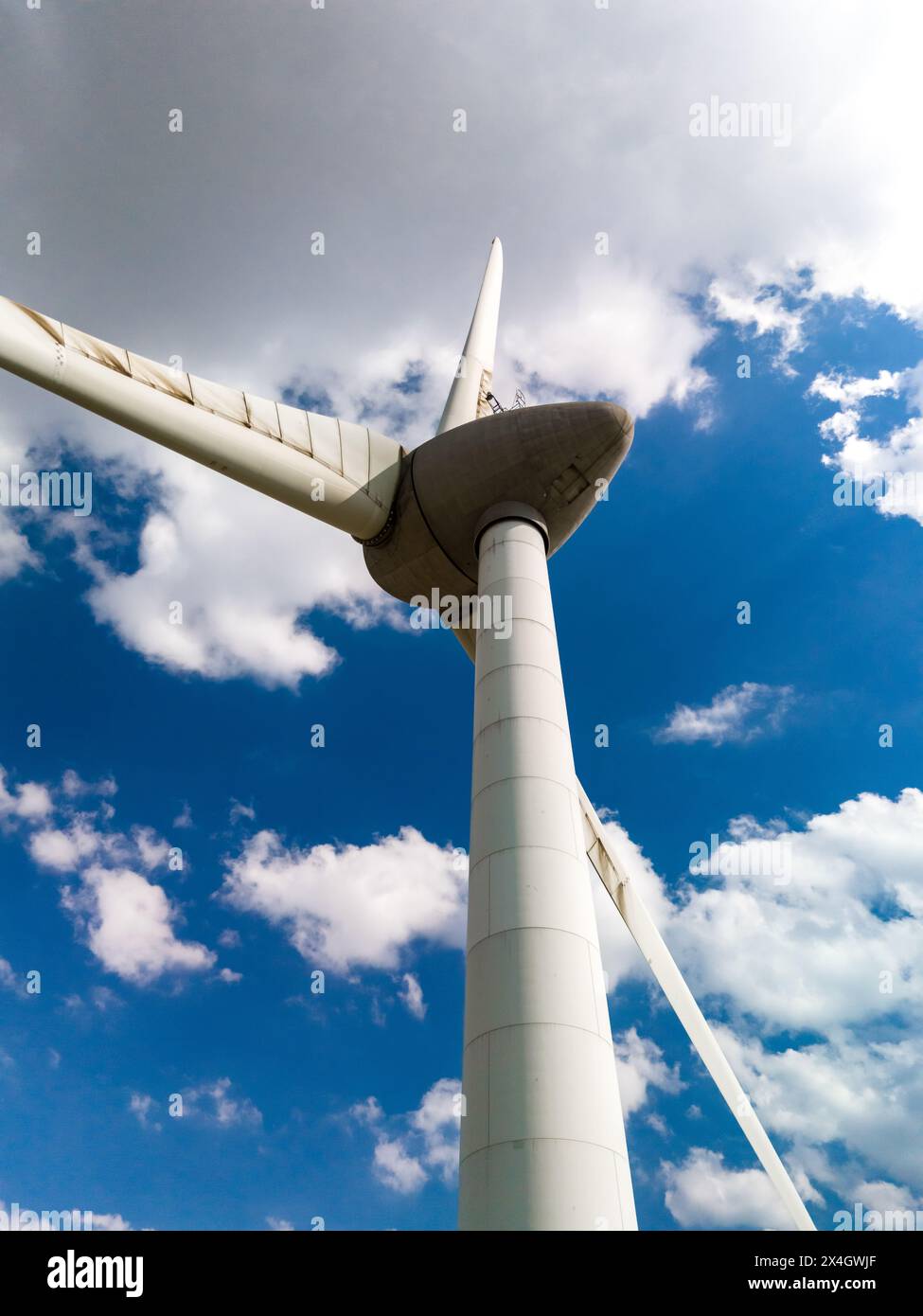 Eine Windturbine dreht sich anmutig vor einem leuchtend blauen Himmel im niederländischen Flevoland. Stockfoto