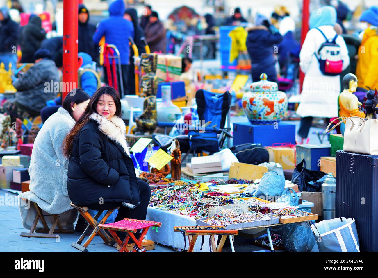 Schöne junge Frauen, die sich um ihren Stand auf dem Panjiayuan Antiquitätenmarkt kümmern, Peking, China. Dies ist auch ein Flohmarkt am Wochenende. Stockfoto