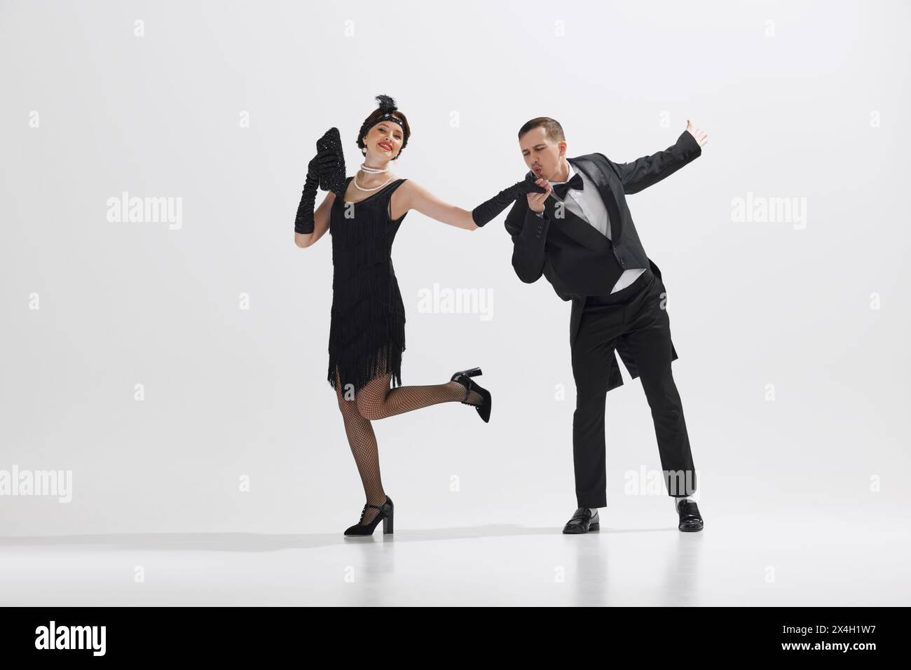 Junges Paar im Stil der 1920er Jahre, eleganter Mann und Frau, die isoliert vor weißem Studiohintergrund tanzen Stockfoto