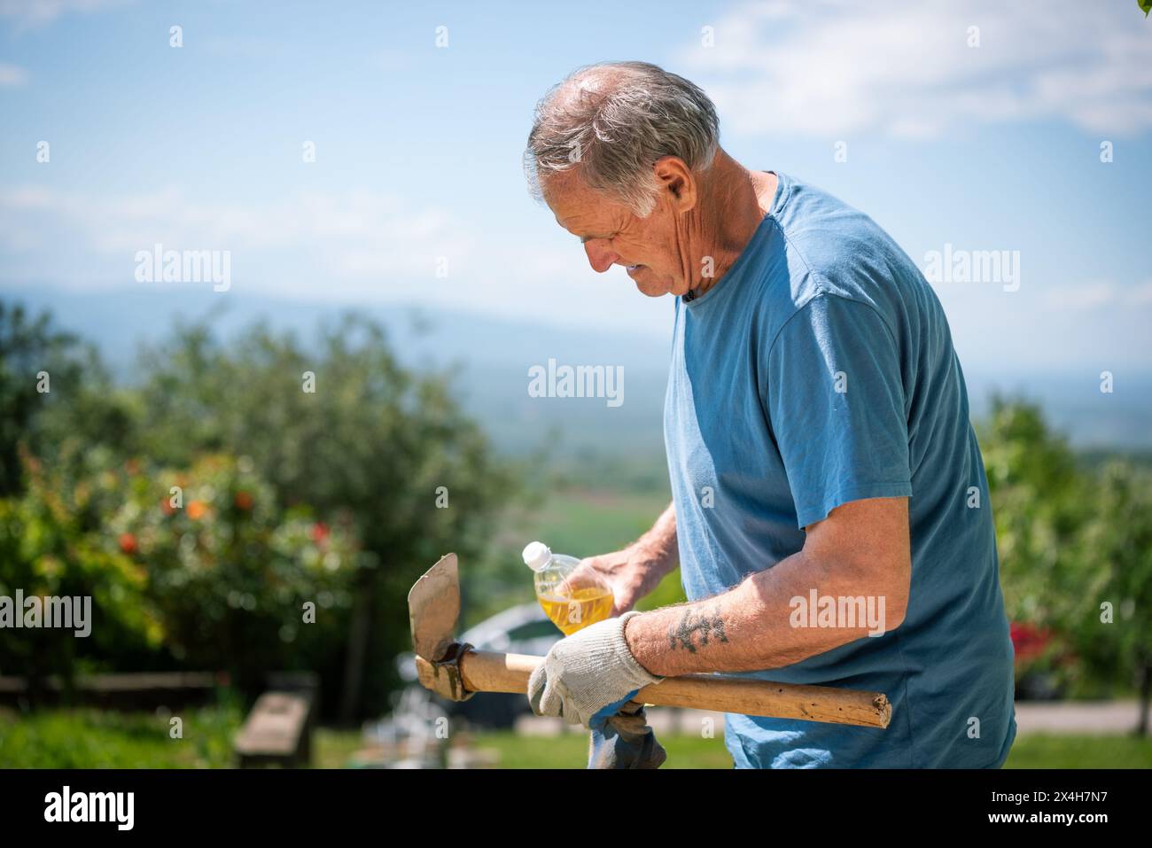 Ein älterer Mann repariert sein Gartengerät Stockfoto