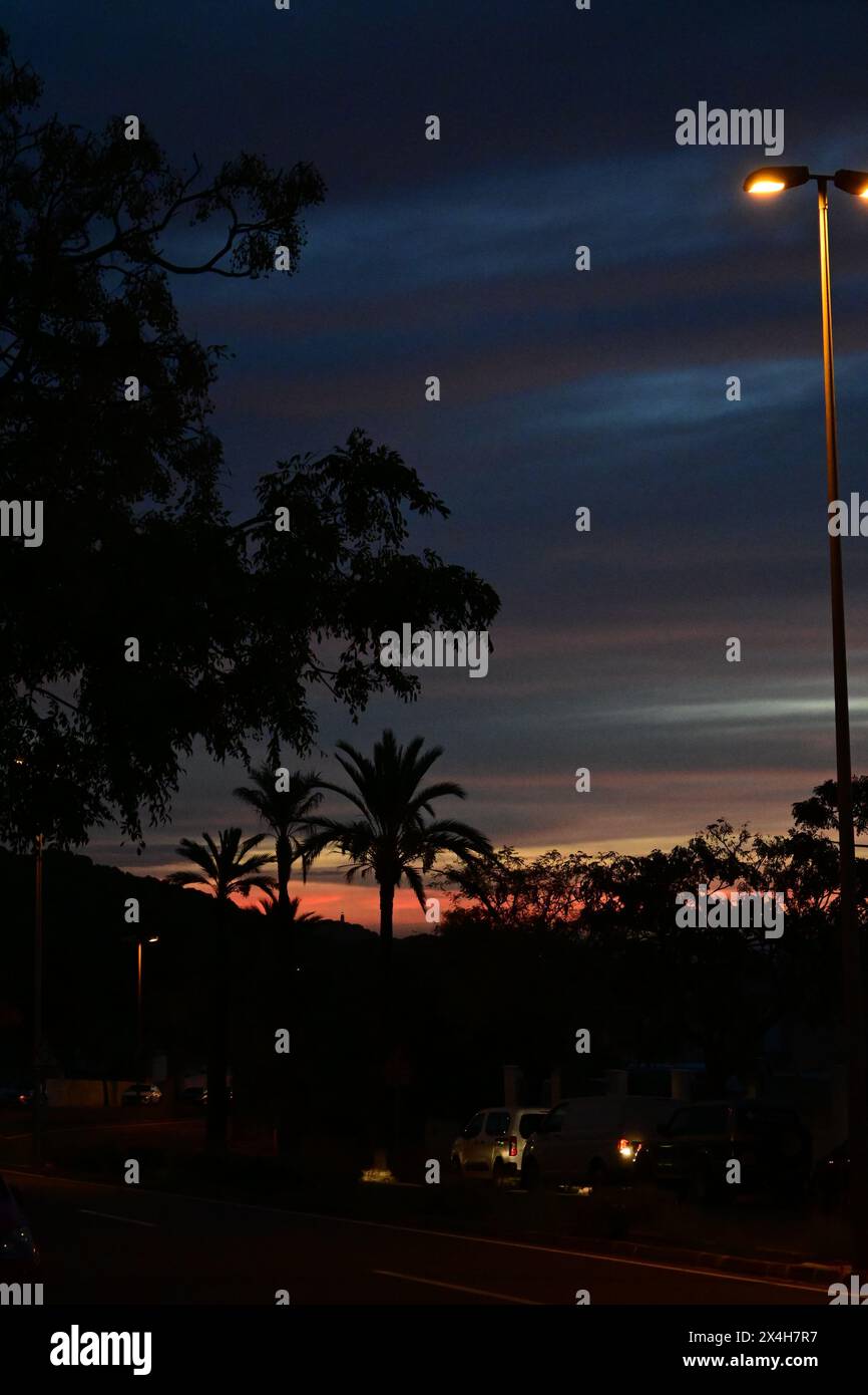 Ein ruhiger Abendspaziergang mit Straßenlaternen, die in der Dämmerung eine ruhige Stadtstraße erleuchten, warme Lichter auf die Gebäude werfen und eine friedliche Atmosphäre schaffen Stockfoto