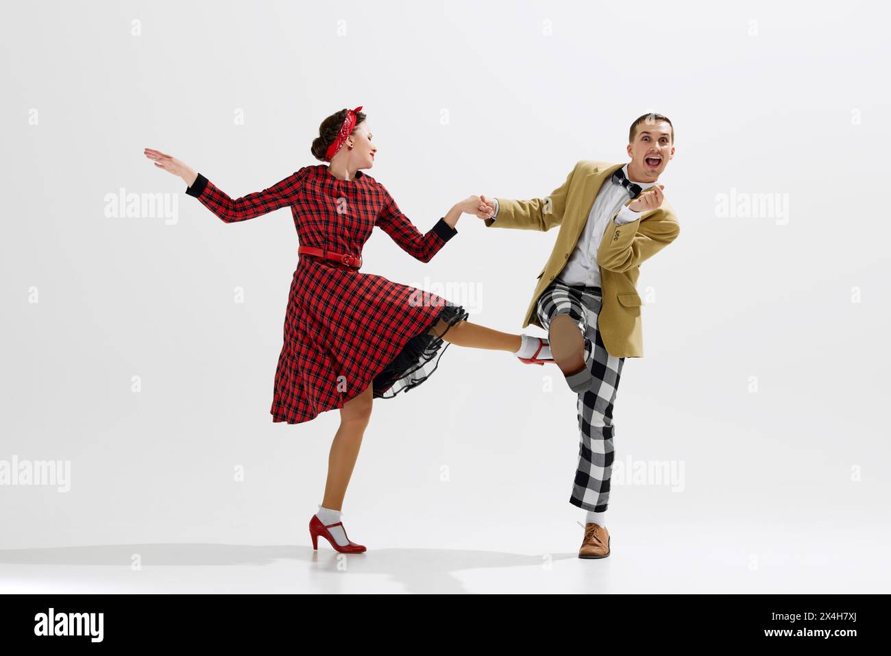 Boogie Woogie. Stilvoller junger Mann und elegante Frau, die emotional isoliert über weißem Studiohintergrund tanzen Stockfoto