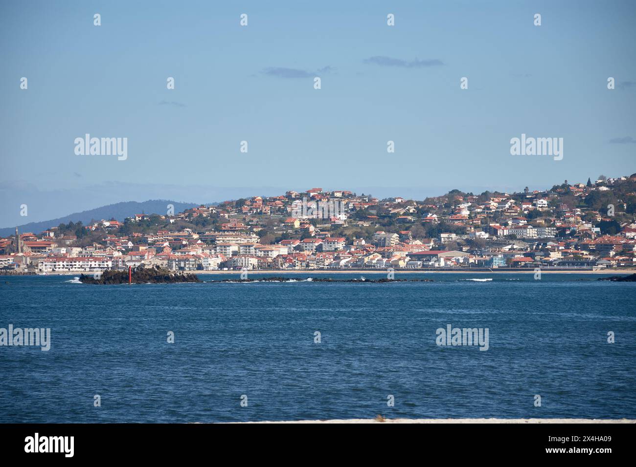Playa America mit kleinen Häusern an der Küste mit türkisblauem Meer und klarem Himmel in Nigran, Pontevedra, Spanien Stockfoto