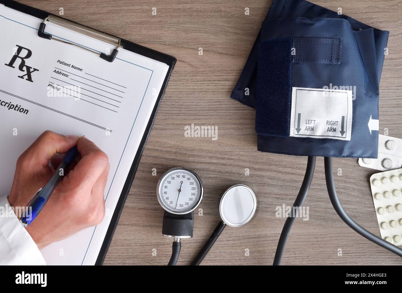 Konzept der Überwachung der Herzgesundheit und des Blutdrucks mit dem Arzt, der Medikamente auf einem Holztisch verschreibt. Draufsicht. Stockfoto