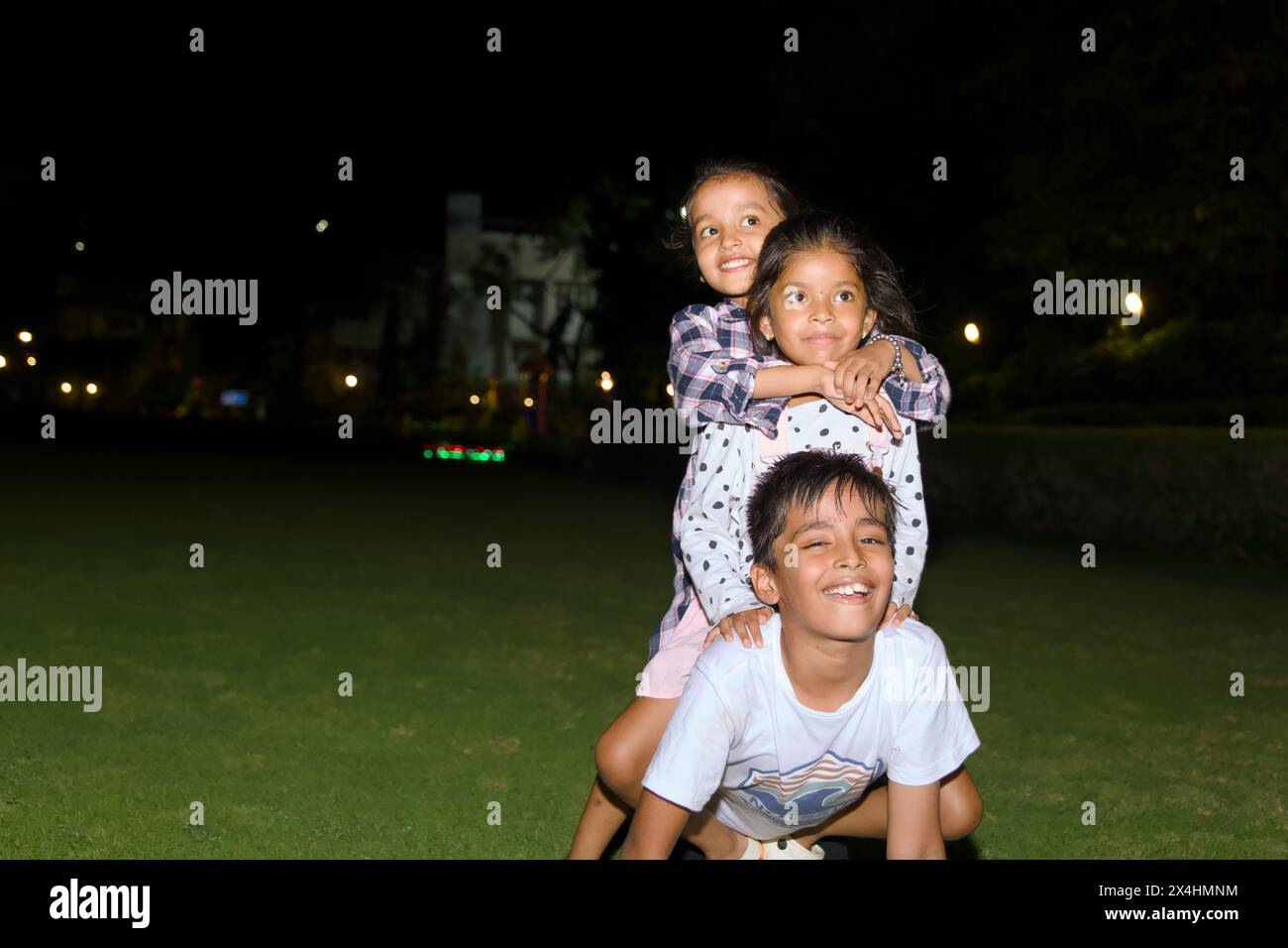 Dieses Bild ist von glücklichen drei Kindern, die zusammen im Park bei Nacht Lifestyle Concept spielen Stockfoto
