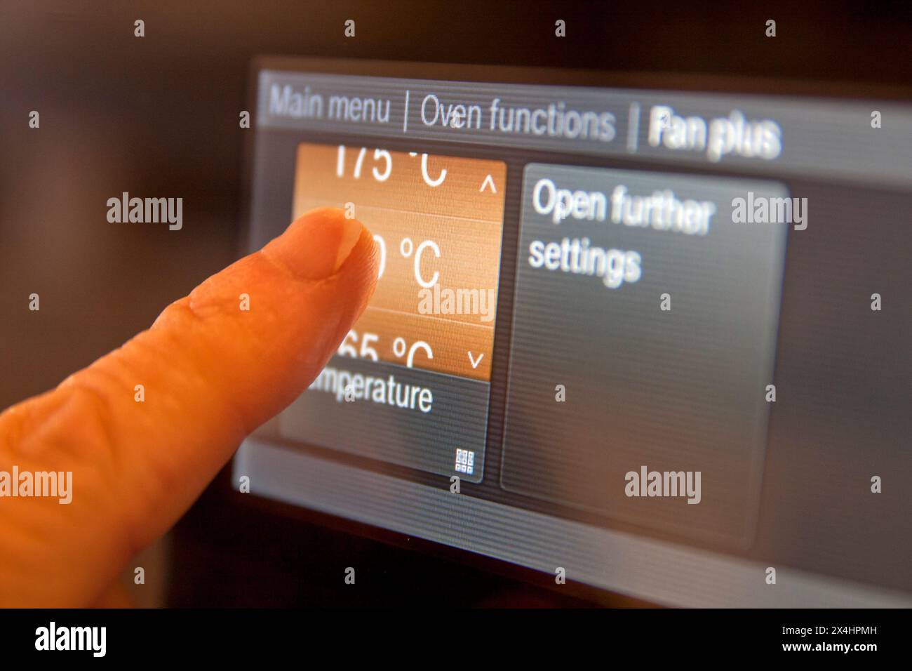 Temperaturfunktionen für Erwachsene per Finger auf programmierbaren Haushaltsöfen Stockfoto