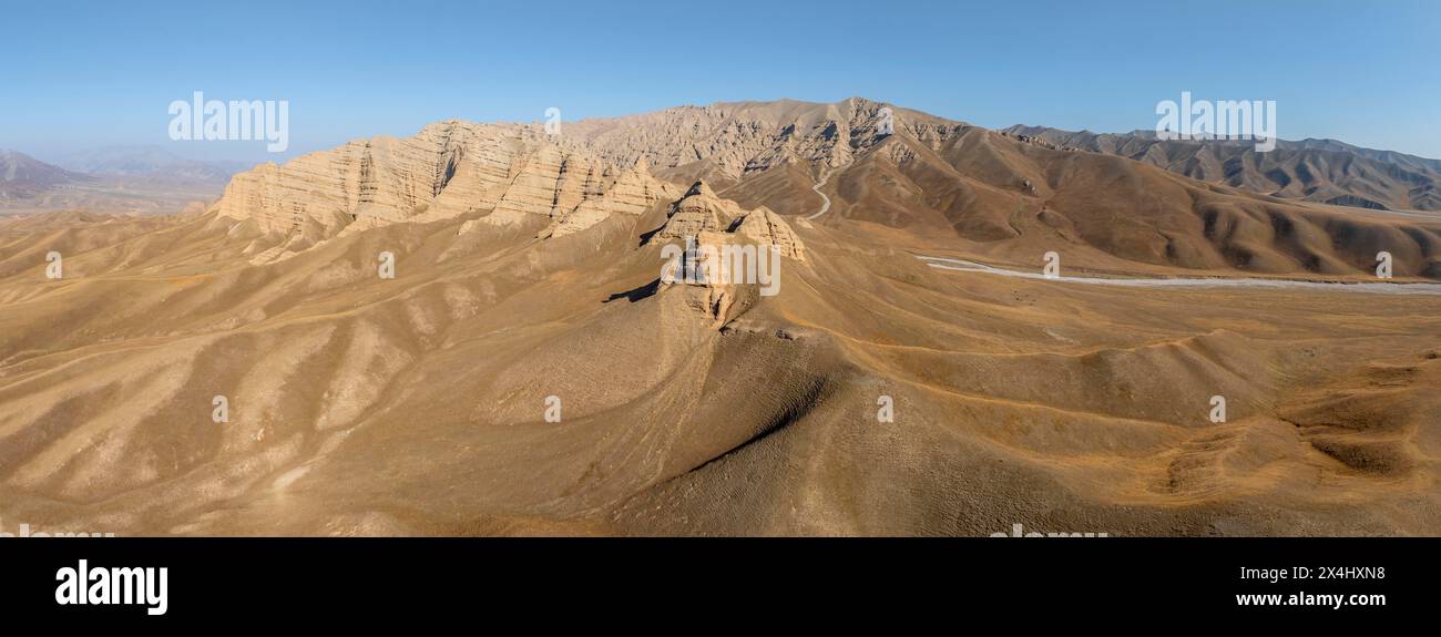 Berglandschaft mit steilen Felsen, erodierten Felsformationen zwischen gelben Hügeln, in der Nähe von Baetov, Naryn Region, Kirgisistan Stockfoto