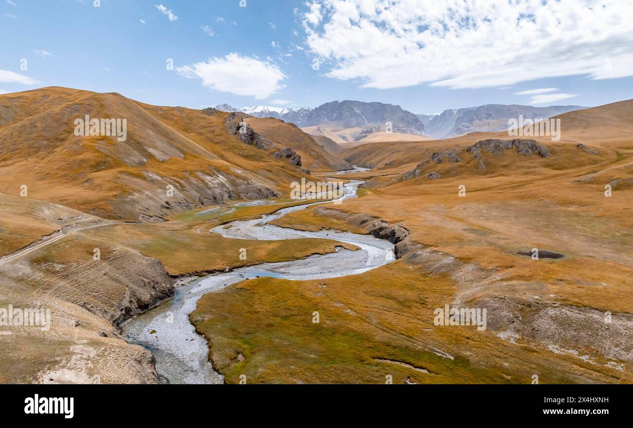 Aus der Vogelperspektive schlängelt sich der Fluss Kol Suu durch ein Bergtal mit Hügeln aus gelbem Gras, Provinz Naryn, Kirgisistan Stockfoto