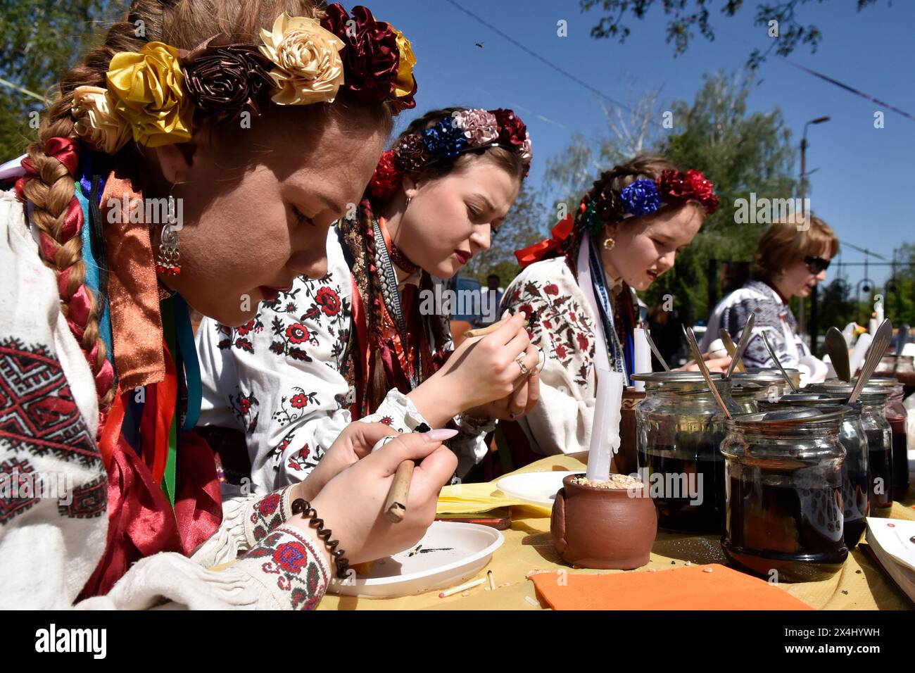 VINNYTSIA, UKRAINE - 1. MAI 2024 - Mädchen in ukrainischen Nationalkostümen machen Pysankas (ukrainische Ostereier) während der Vorosterveranstaltung Zapletemo Shuma im Kreativraum Schtschedryk, Winnytsia, West-Zentral-Ukraine. Stockfoto