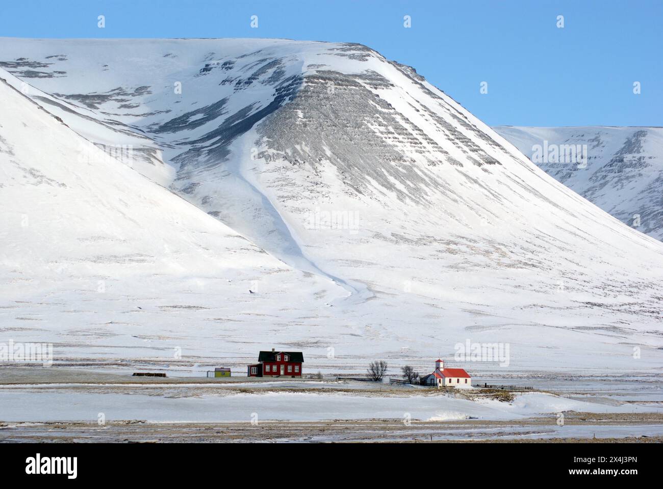 Ein Einzelhaus und eine kleine Kirche in einer einsamen Winterlandschaft Stockfoto