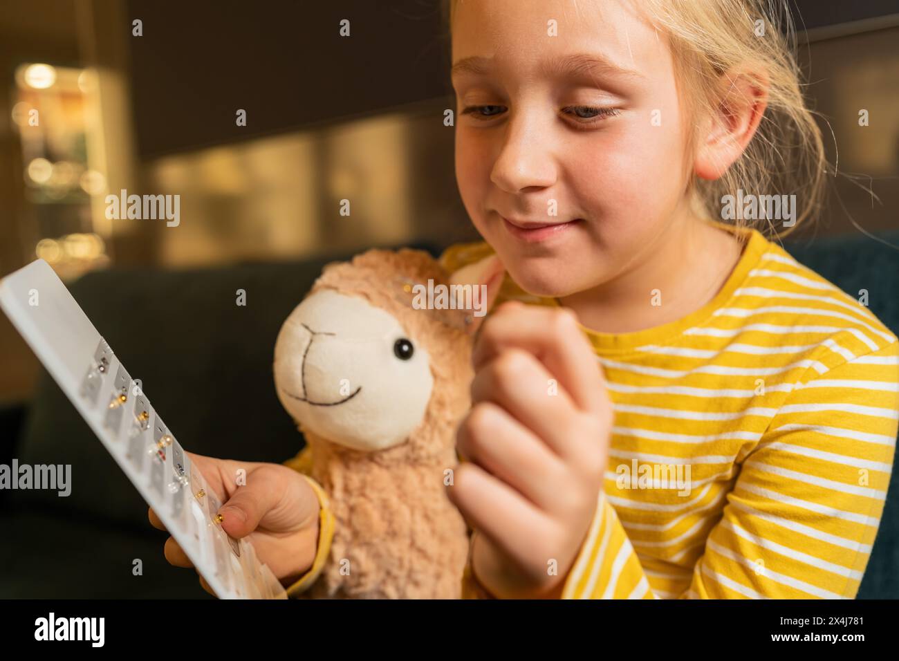 Ein glückliches Mädchen, das ein Plüschtier und einen Ohrring in der Hand hält und einen Ohrring im Juweliergeschäft ansieht Stockfoto