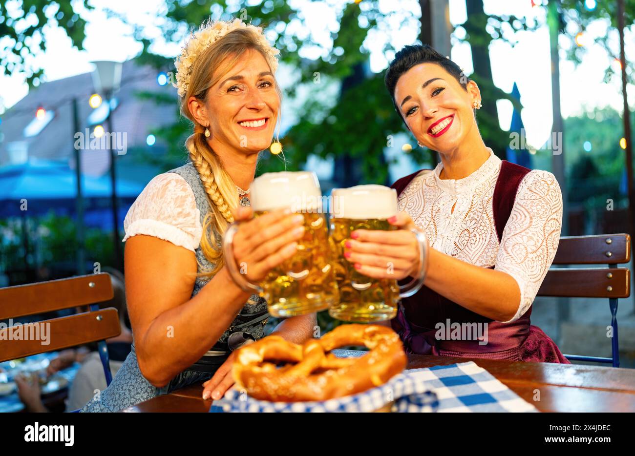 Bayerische Freunde in Tracht oder Dirndl, das bei Bier im Biergarten oder oktoberfest in Bayern tobt Stockfoto