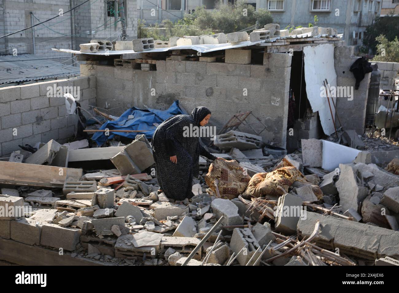 Gaza. Mai 2024. Eine Frau sammelt Gegenstände aus den Trümmern eines zerstörten Gebäudes nach einem israelischen Luftangriff in Rafah im südlichen Gazastreifen am 3. Mai 2024. Die Zahl der palästinensischen Todesopfer durch die laufenden israelischen Angriffe auf den Gazastreifen ist auf 34.622, wie die Gesundheitsbehörden des Gazastreifens in einer Pressemitteilung am Freitag mitteilten. Quelle: Khaled Omar/Xinhua/Alamy Live News Stockfoto