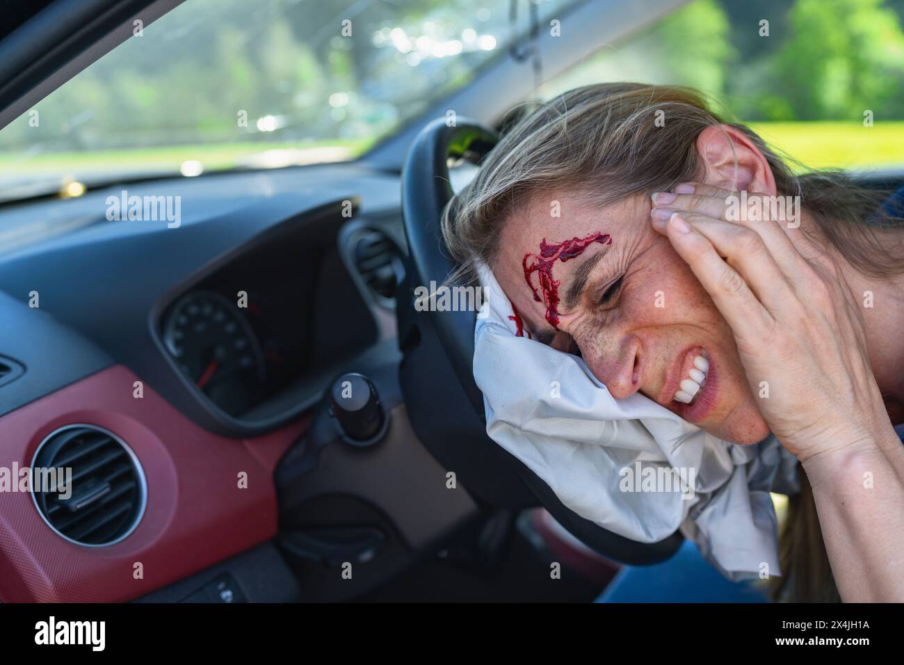 Verletzte Frau mit Kopfwunde, die in einem abgestürzten Auto sitzt Stockfoto