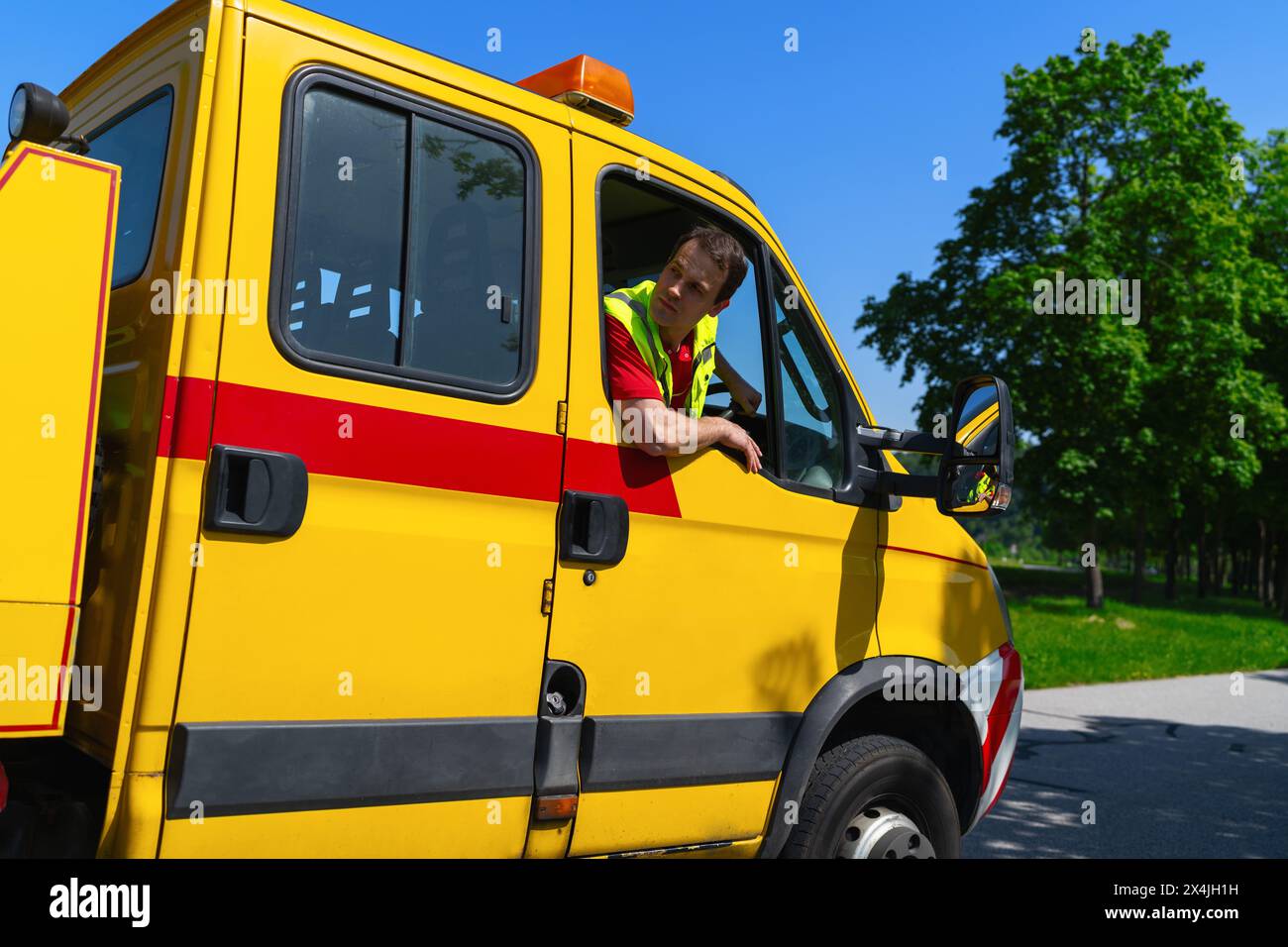 Fahrer eines Abschleppwagens, der in einem gelben Lkw sitzt und aus dem Fenster blickt und prüft, ob er manövrieren kann Stockfoto