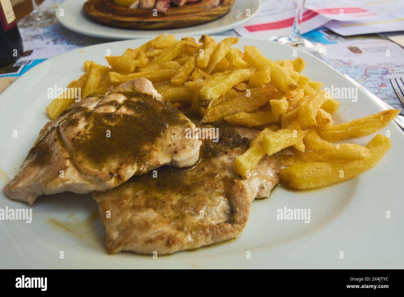 Typische Speisen auf dem Restauranttisch mit Karte als Tischdecke, die das Wesen der lokalen Küche in einer Reiseatmosphäre einfangen. Stockfoto