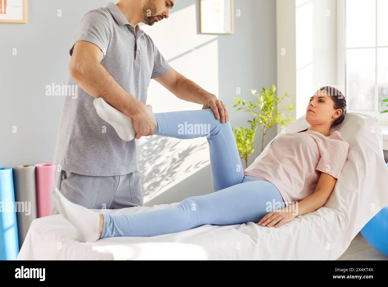 Physiotherapeut behandelt Beinverletzungen und hilft Patienten bei Übungen für die unteren Gliedmaßen. Stockfoto