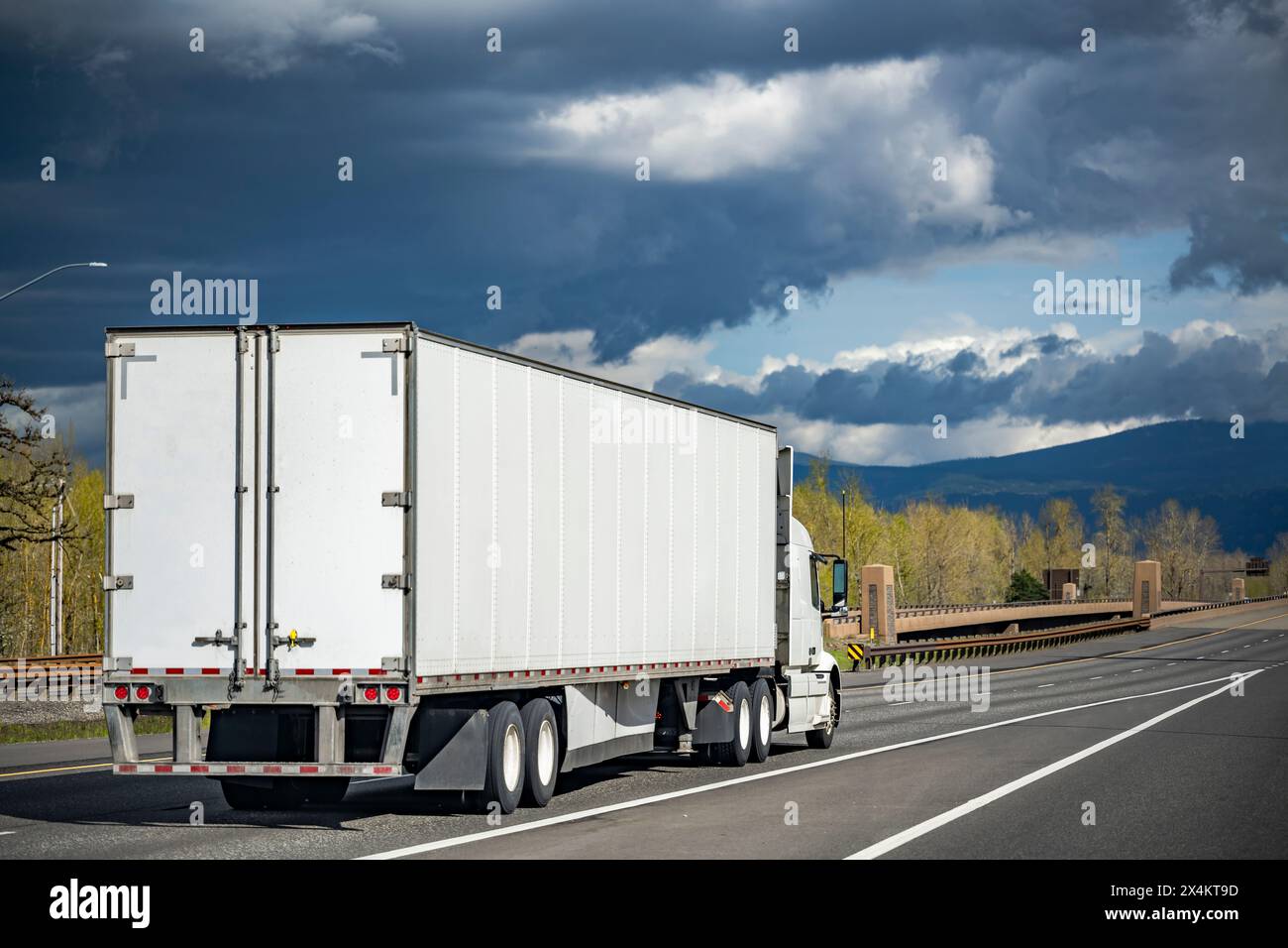 Industrieträger, weißer großer Lkw-Sattelzugmaschine mit verlängerter Kabine für LKW-Fahrer-Ruhestellung, Transport von gewerblicher Ladung im Trocken-Van-Auflieger-Antrieb Stockfoto