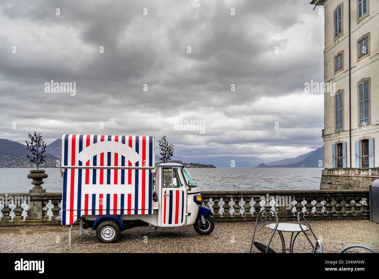 Dreirädriges motorisiertes Fahrzeug zum Verkauf von Eis, das auf der Terrasse des Borromeo-Palastes auf der Isola Bella geparkt ist - Panoramablick auf den Lago Maggiore Stockfoto