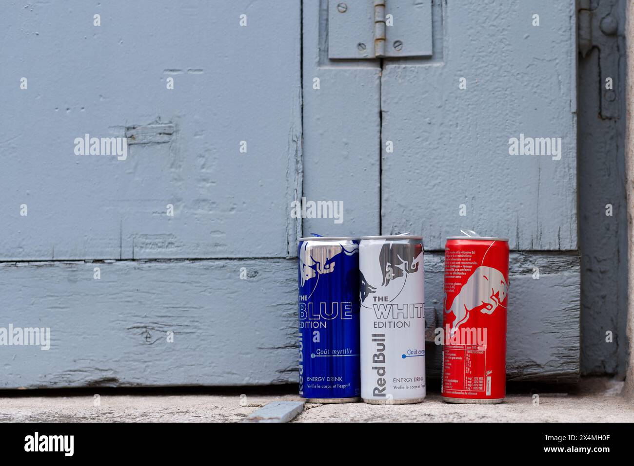 Lyon, Frankreich. Drei Dosen Red Bull Energy Drink in den Farben Blau, weiß und Rot stehen auf einer Fensterbank. Kopierbereich Stockfoto