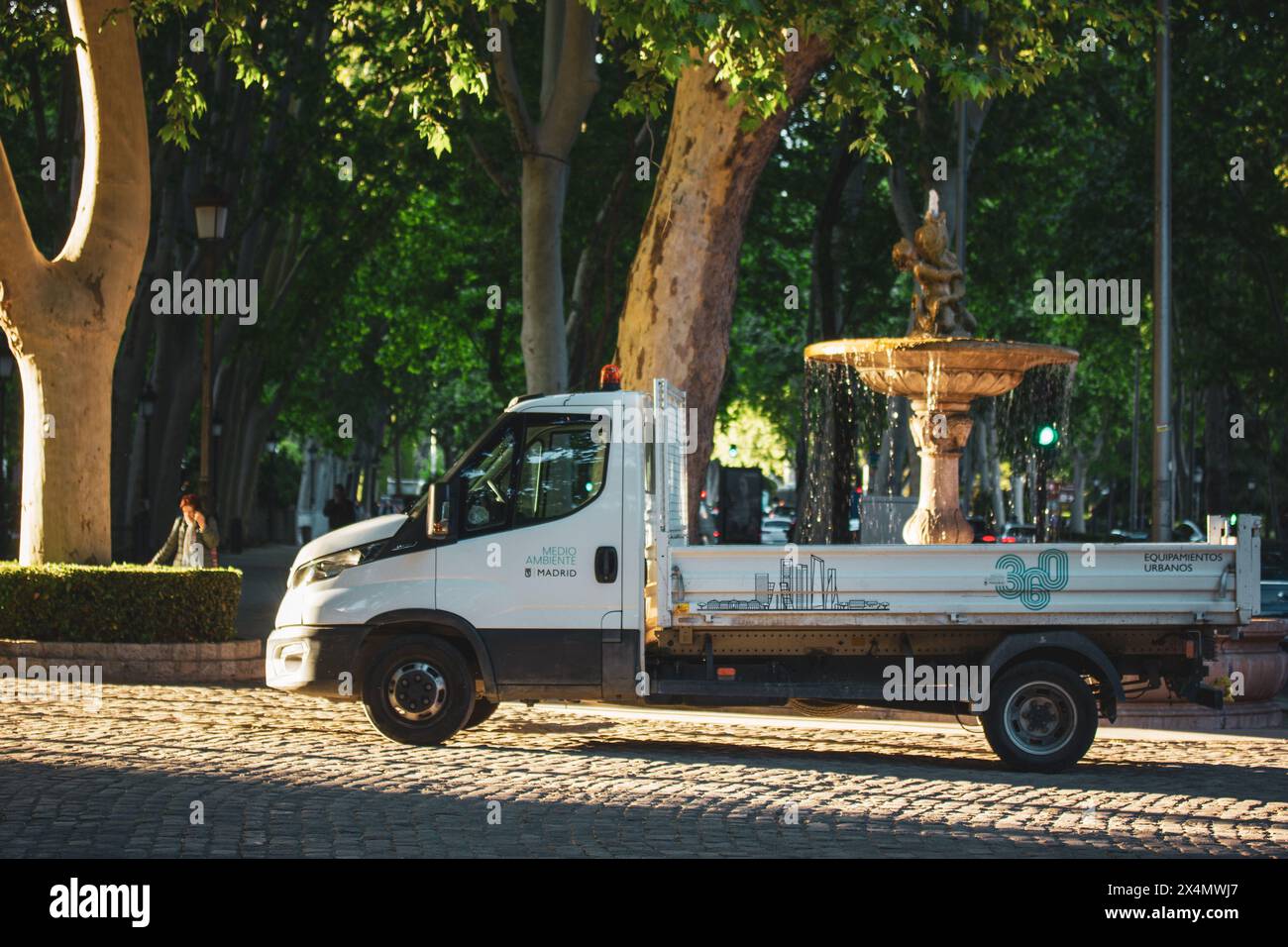 Madrid, Spanien. 1. Mai 2024 offener Truck im Stadtpark. Kompaktes Auto, weißer Van vor einem alten Brunnen auf der Altstadtstraße. Offener Muldenkipper. Stockfoto