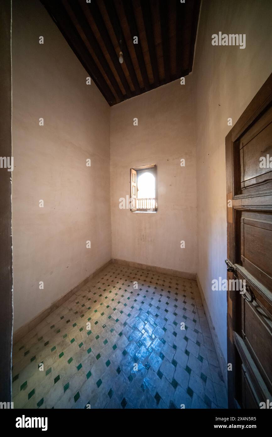 Spärliches Studentenzimmer mit traditionellen Fliesen und kleinem Fenster im Cherratine Madrasa. Fès, Marokko. Stockfoto