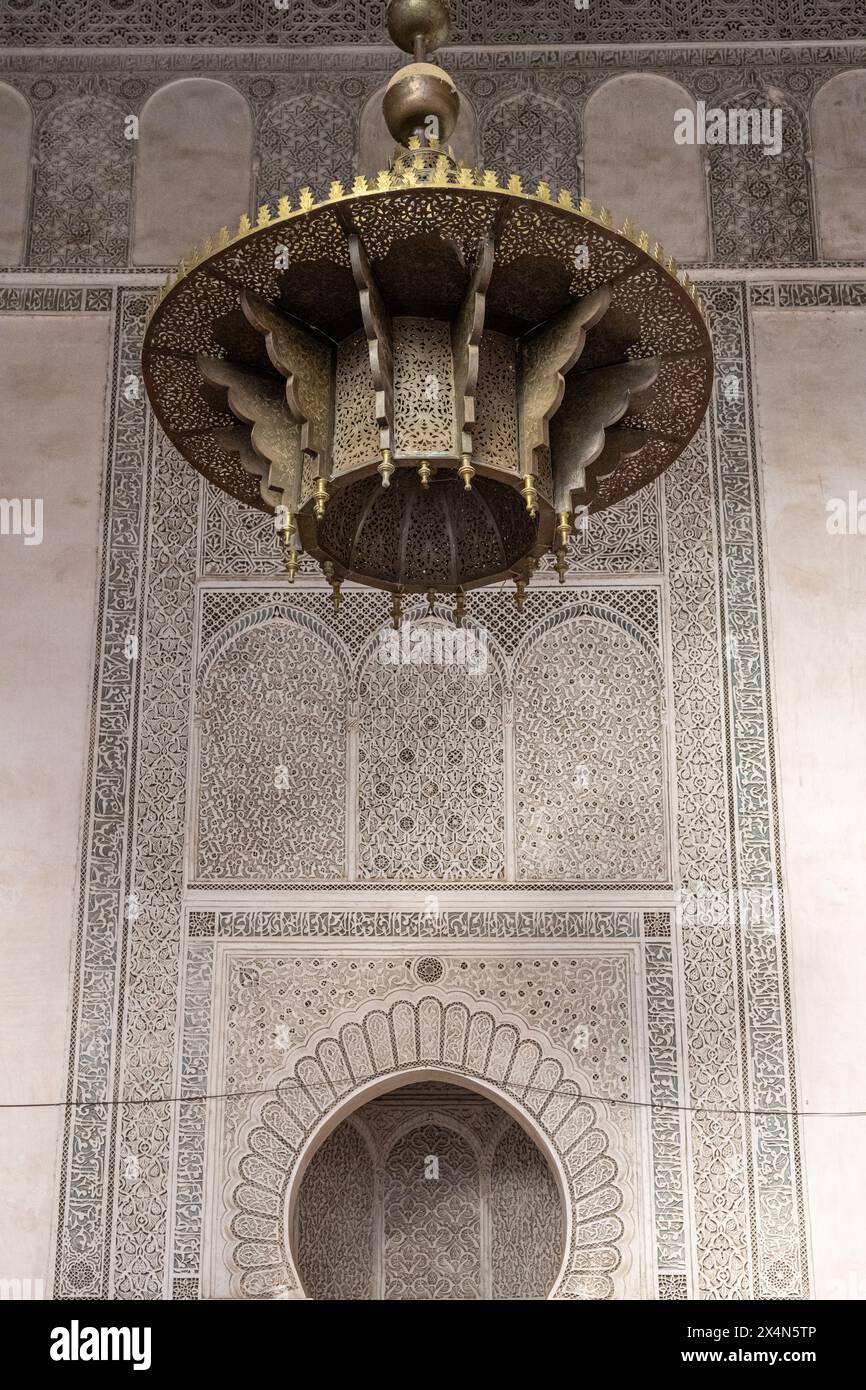 Eine Bronzelampe hängt vor der komplexen Kulisse des Cherratine Madrasa., Fes, Marokko. Stockfoto