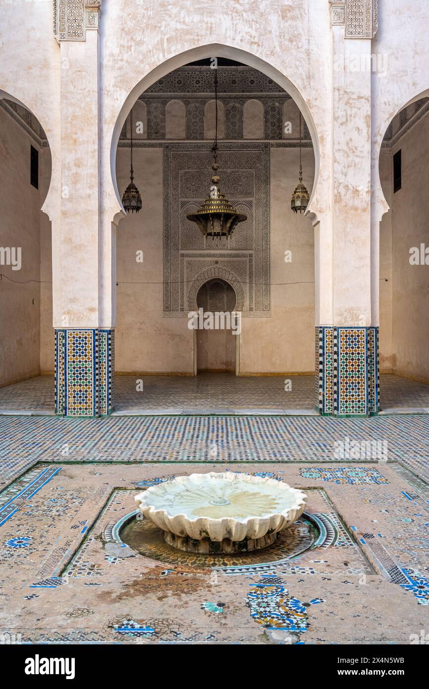 Ruhiger Innenhof mit einem traditionellen Brunnen mit komplizierten Fliesen in Fès, Marokko. Stockfoto