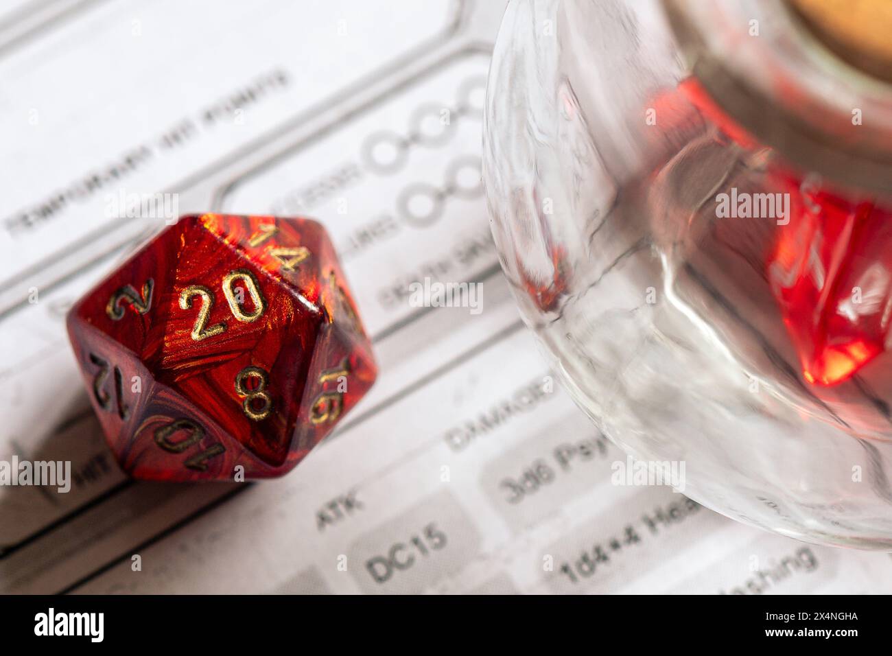 Rote D20 Würfel neben einem Glasglas auf einem Zeichenblatt, wobei der Schwerpunkt auf Strategie und Entscheidungsfindung in Rollenspielen liegt. Stockfoto