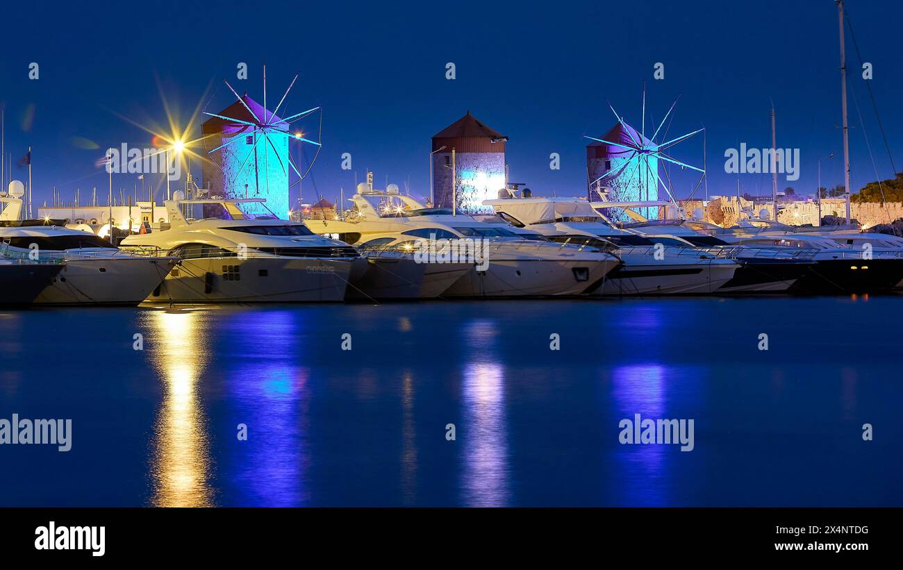 Marina mit beleuchteten Windmühlen, die während der blauen Stunde im Wasser reflektiert werden, Dämmerung, Mandraki Hafen, Rhodos, Dodekanese, Griechische Inseln, Griechenland Stockfoto