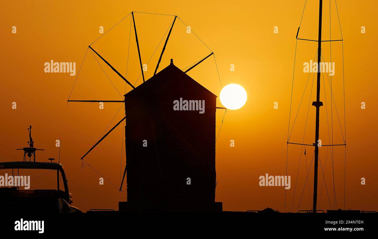 Silhouette einer Windmühle vor der aufgehenden Sonne mit einem warmen Farbverlauf, Dämmerung, Mandraki Hafer, Rhodos, Dodekanese, Griechische Inseln, Griechenland Stockfoto