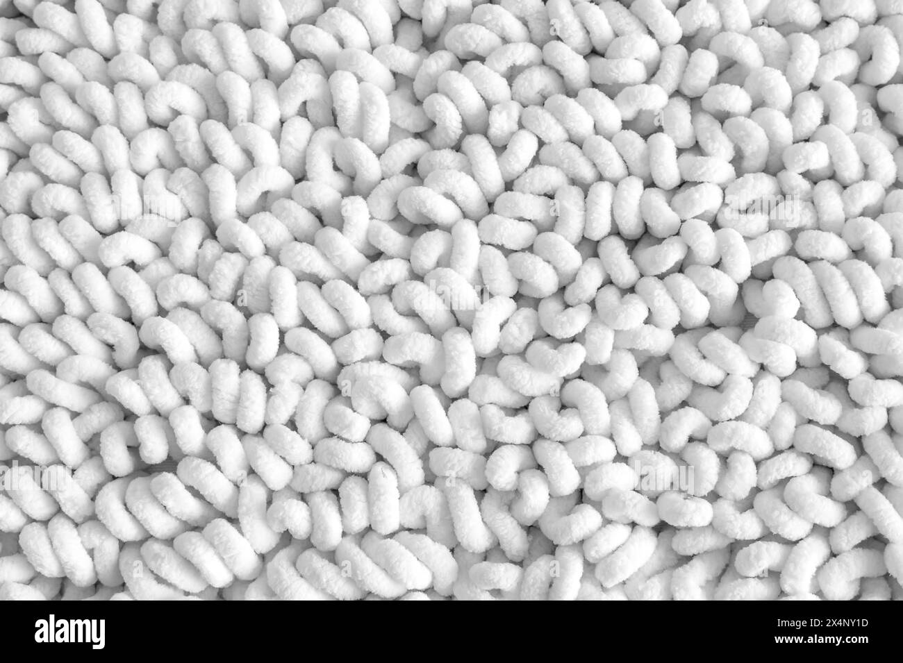 Geschwungener Baumwollstoff. Stricke aus Plüschgarn zum Handstricken mit fertig gefertigten Schlaufen. Hintergrund aus einem Satz lockiger Vliesfäden. Garn mit Schlaufen. Ne Stockfoto