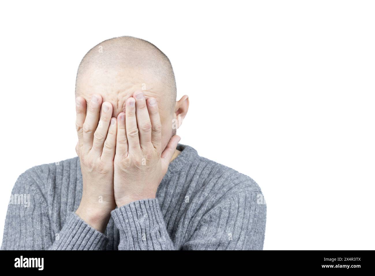 Das ist ein fesselndes Porträt eines Mannes vor einem weißen Hintergrund, dessen Hände sein Gesicht in einer universellen Geste der Verzweiflung bedecken. Stockfoto