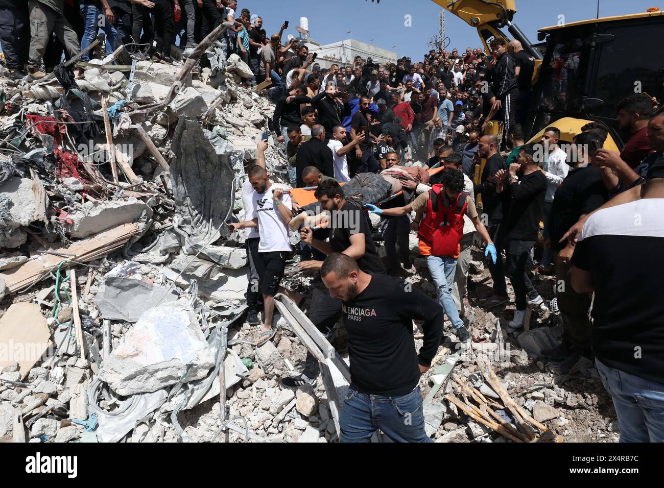(240505) -- TULKARM, 5. Mai 2024 (Xinhua) -- Ein Opfer wird nach einer Militäroperation israelischer Streitkräfte in Deir Al-Ghusoun, einer Stadt im nördlichen Westjordanland Tulkarm am 4. Mai 2024, versetzt, als Palästinenser durch die Trümmer gehen. Mindestens sechs Palästinenser wurden am Samstag bei einer Militäroperation israelischer Streitkräfte in Deir Al-Ghusoun, einer Stadt im nördlichen Westjordanland Tulkarm, getötet. Sicherheitsquellen in Palästina sagten, israelische Truppen hätten eine Residenz in der Stadt für mehr als 15 Stunden eingekreist, während dieser Zeit Stockfoto