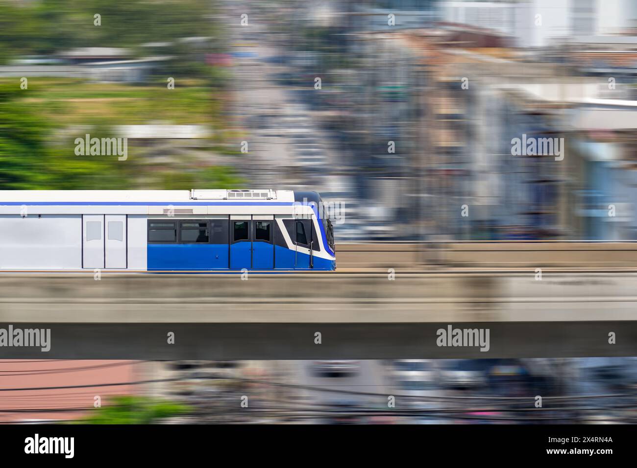 Schnelle moderne Pendlerzüge, Bewegungsunschärfe fahren auf einer Brücke durch Gebäude in Höhe, Seitenansicht. Stockfoto