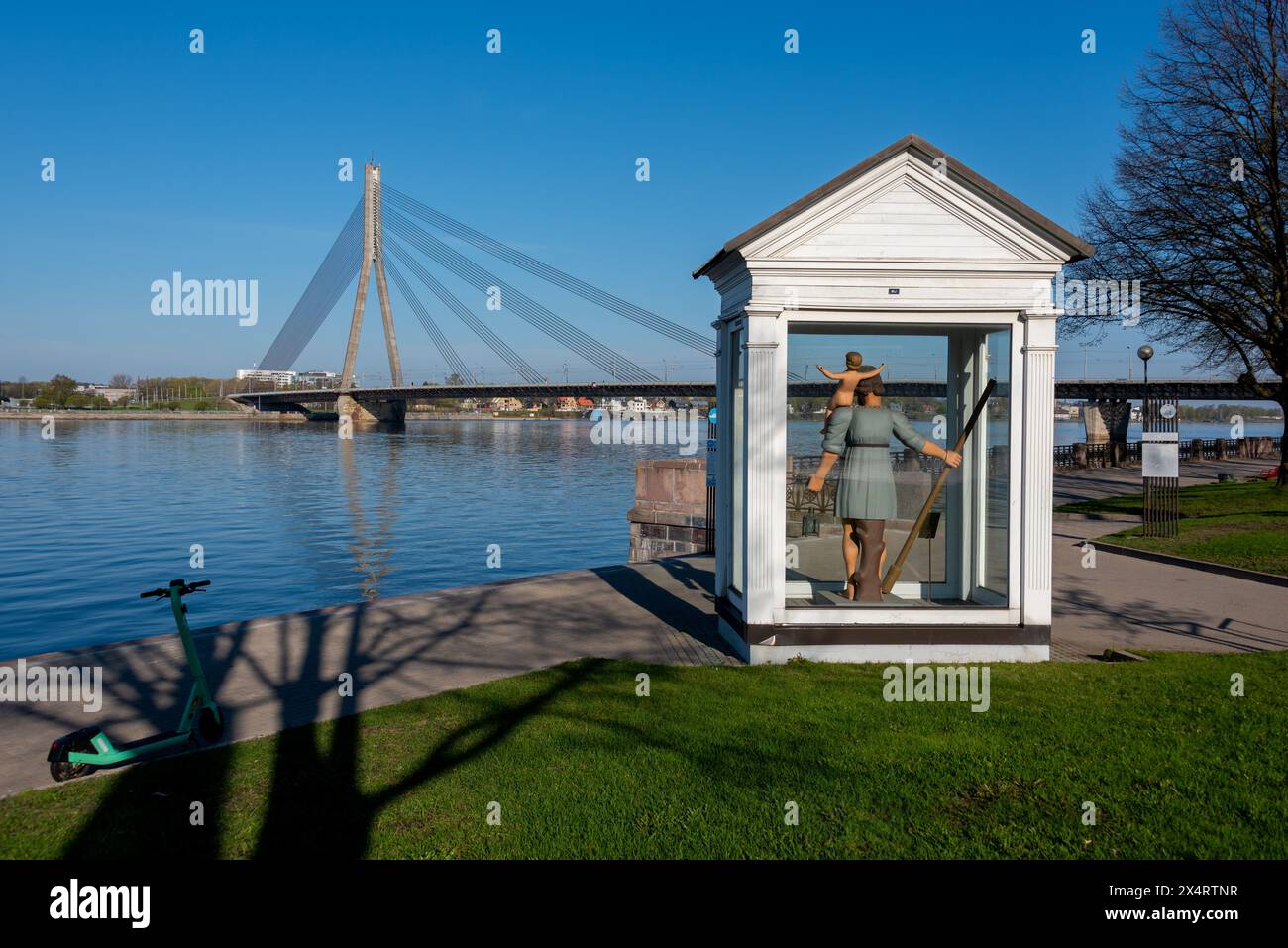 Denkmal für den hl. Christoph dem Großen, Schutzpatron von Riga, mit dem Fluss Daugava und der Brücke Vanšu im Hintergrund, Riga, Lettland Stockfoto