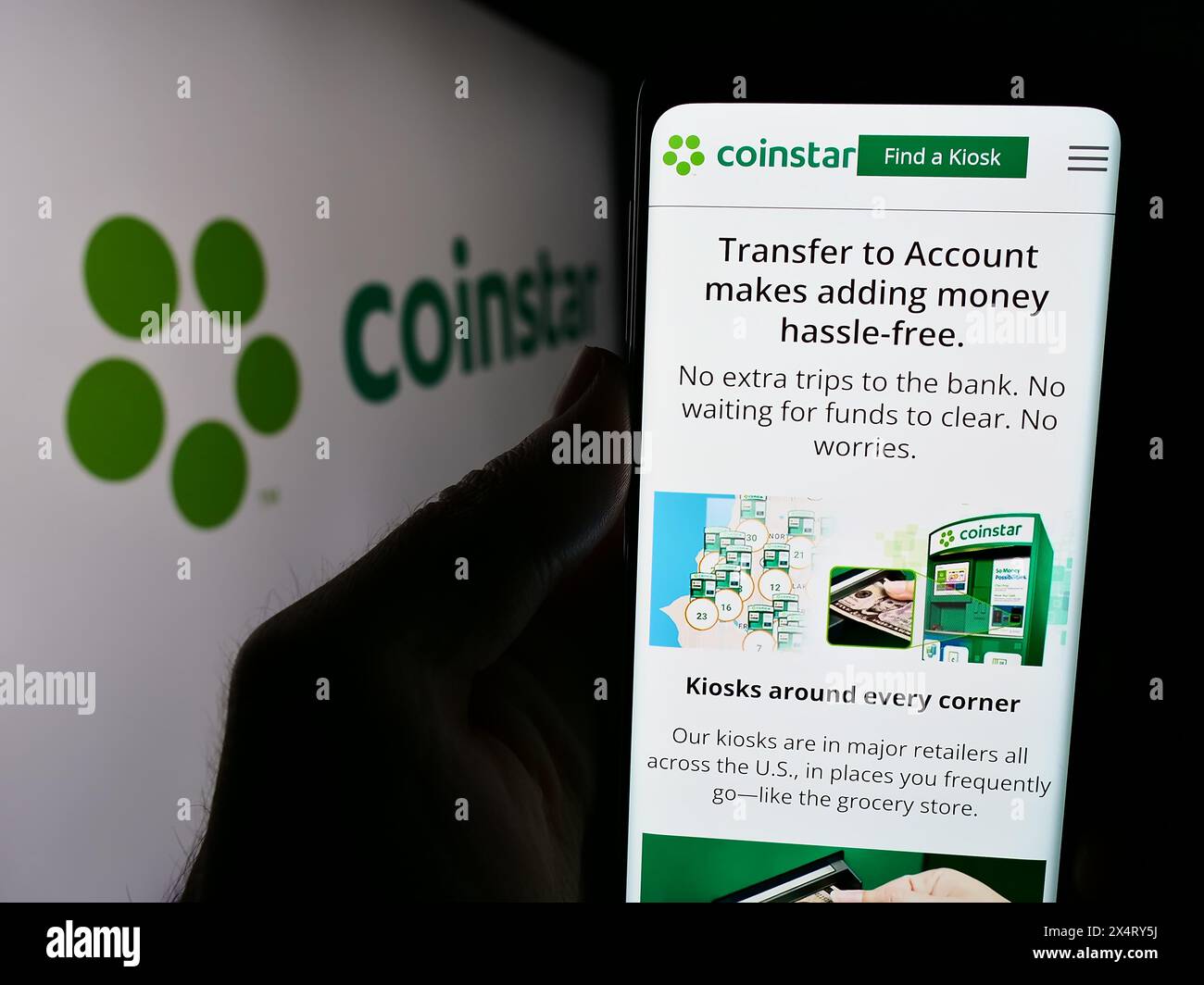 Person, die ein Smartphone hält, mit der Webseite des US-amerikanischen Münzautomaten-Unternehmens Coinstar LLC vor dem Logo. Konzentrieren Sie sich auf die Mitte des Telefondisplays. Stockfoto