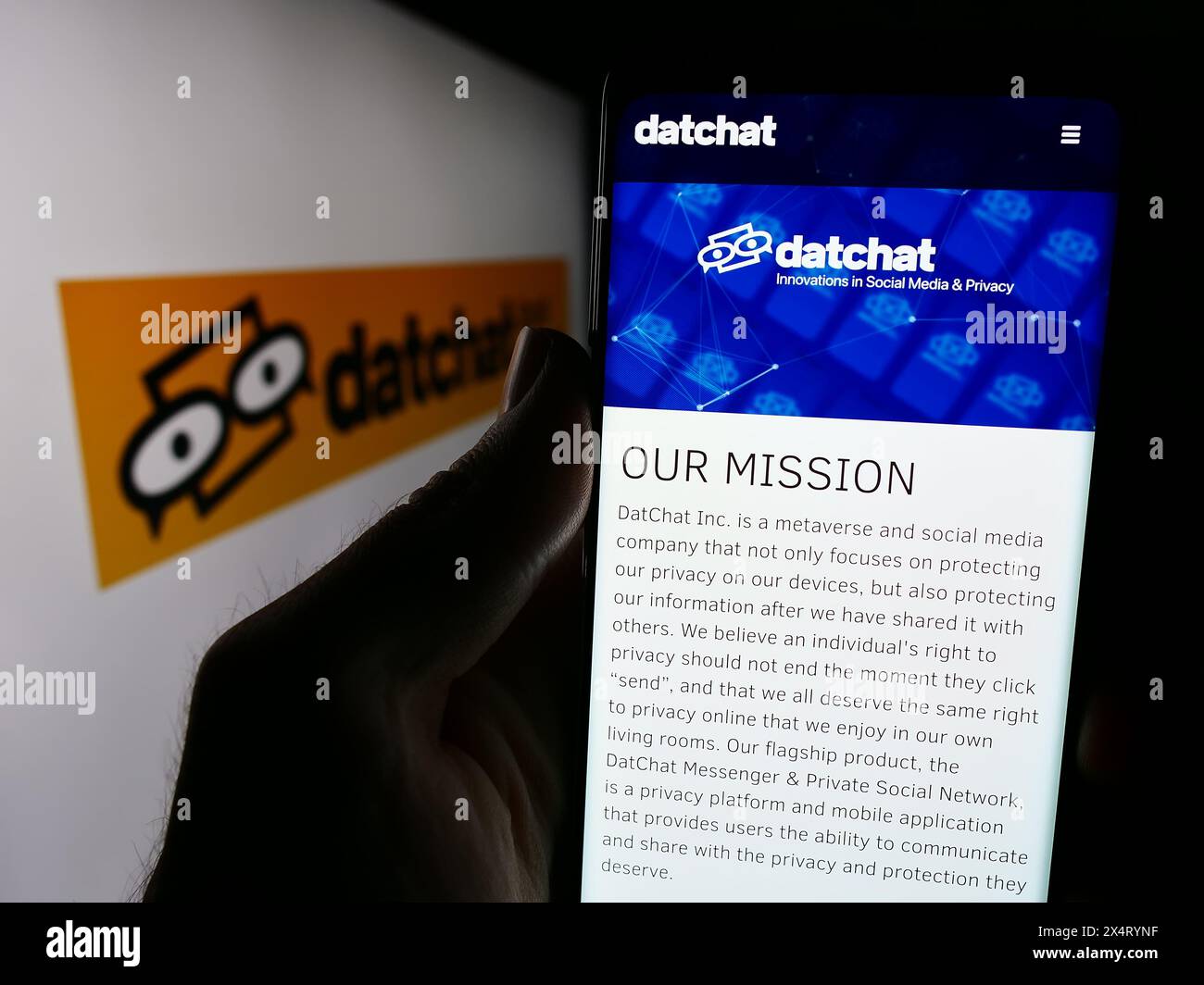 Person, die ein Mobiltelefon hält, mit der Webseite des US-amerikanischen Metaverse- und Social-Media-Unternehmens DatChat Inc. Vor dem Logo. Konzentrieren Sie sich auf die Mitte des Telefondisplays. Stockfoto