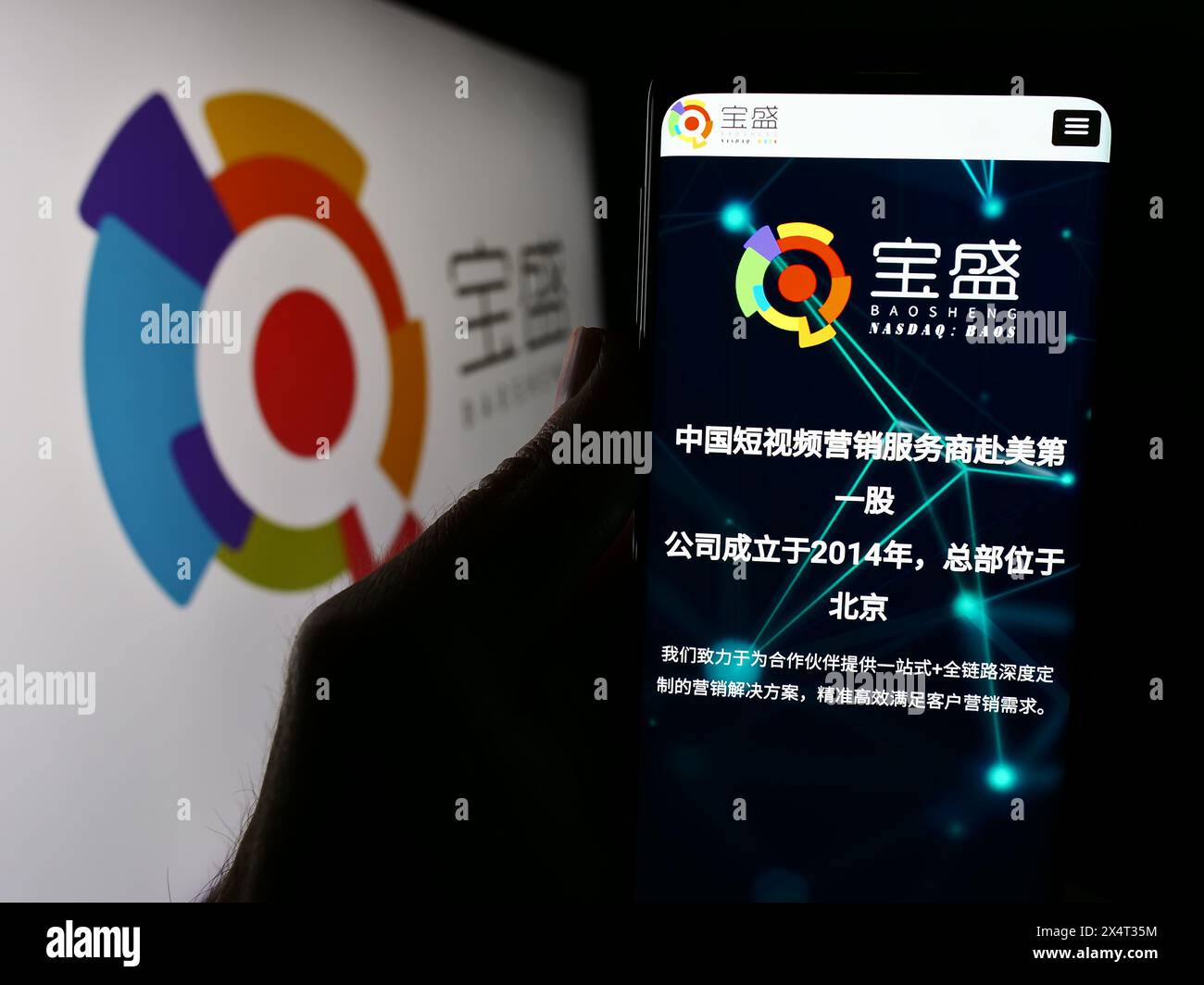 Person, die ein Mobiltelefon hält, mit der Webseite des chinesischen Unternehmens Baosheng Media Group Holdings Limited vor dem Logo. Konzentrieren Sie sich auf die Mitte des Telefondisplays. Stockfoto