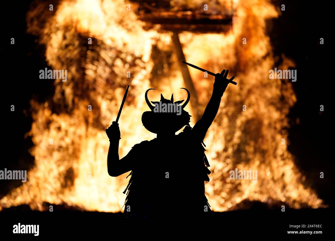 Ein Mitglied der Pentacle Drummers tritt vor einem brennenden Korbmann während des Beltain Celtic Fire Festivals auf der Butser Ancient Farm in der Nähe von Waterlooville, Hampshire, auf. Bilddatum: Samstag, 4. Mai 2024. Stockfoto