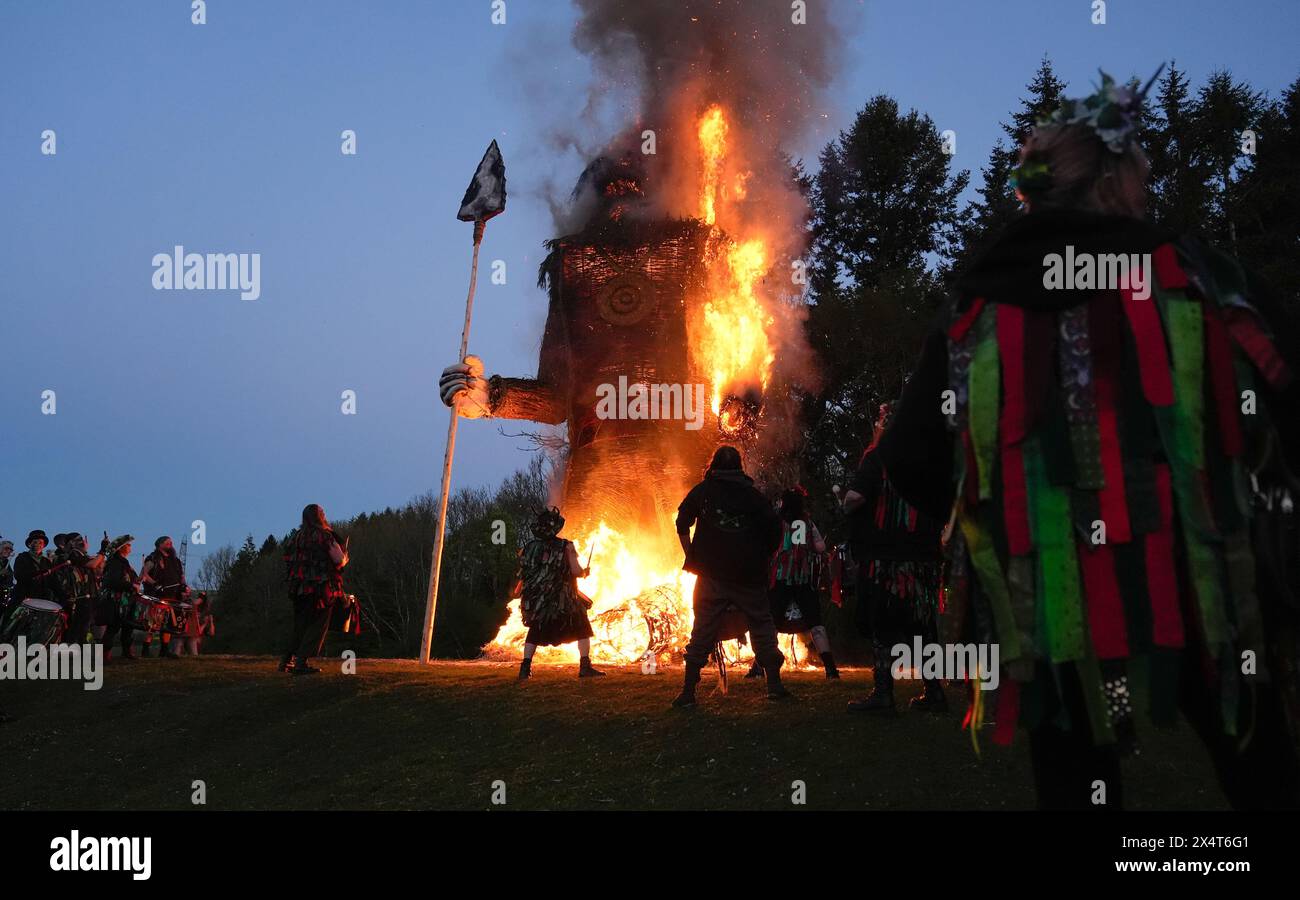 Mitglieder der Pentacle Drummers treten während des Beltain Celtic Fire Festivals auf der Butser Ancient Farm in der Nähe von Waterlooville, Hampshire, vor einem brennenden Korbmann auf. Bilddatum: Samstag, 4. Mai 2024. Stockfoto