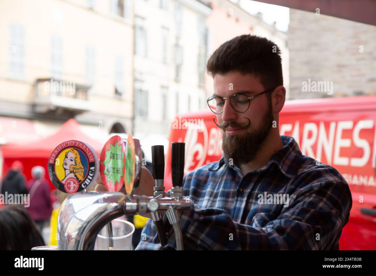 Junger Barkeeper, der Bier auf der Dorfparty gießt Stockfoto