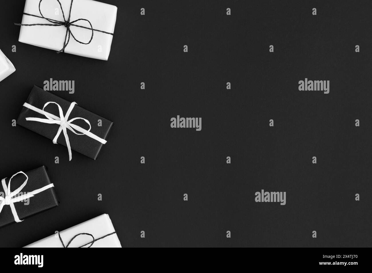 Schwarz-weiße weihnachtsgeschenke auf schwarzem Hintergrund. Flache Ladefläche mit leerem Kopierbereich. Stockfoto
