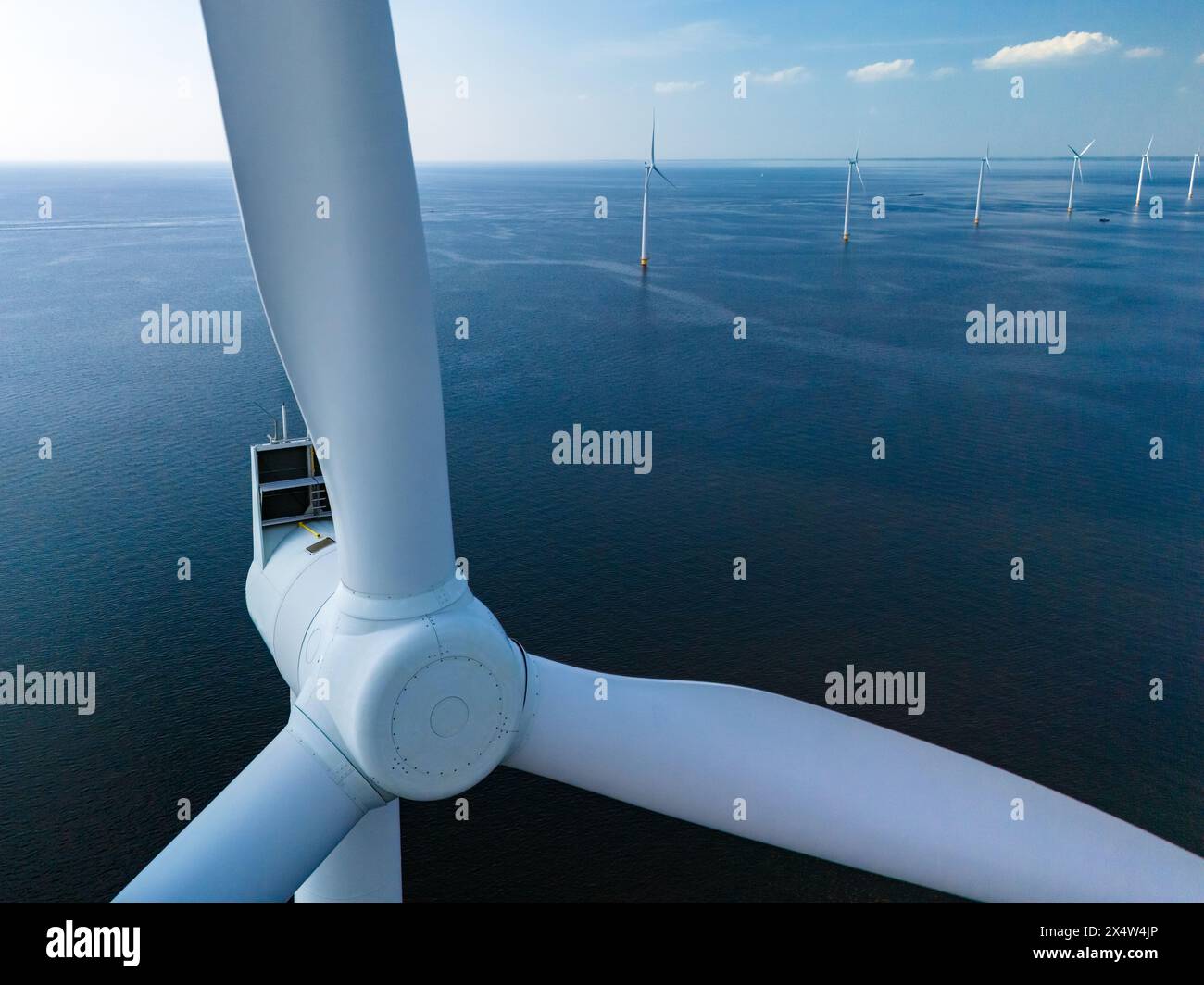 Eine einsame Windenergieanlage dreht sich anmutig in der Weite des Ozeans und nutzt die Kraft des Windes im niederländischen Flevoland. Nahaufnahme des Windes Stockfoto