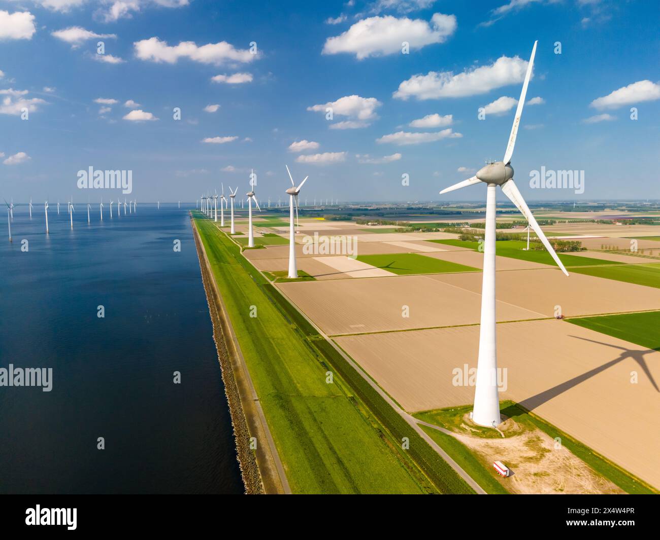 Eine faszinierende Landschaft aus Windturbinen, die sich in einem Windpark an einem ruhigen Gewässer anmutig drehen und nachhaltige Energieerzeugung zeigen. Nein Stockfoto