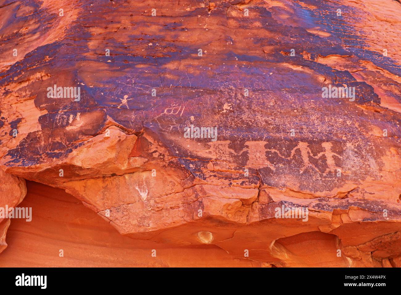 Alte einheimische amerikanische Petroglyphen in Wüstenlack des roten Sandsteins am Mouse's Tank Petroglyph Canyon Trail im Valley of Fire State Park n Stockfoto
